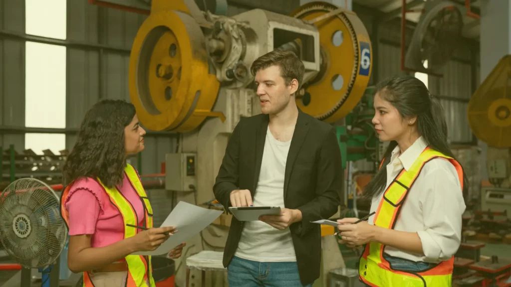 Échange entre ingénieurs et responsables en environnement industriel, illustrant la nécessité de traduire le langage technique pour une prise de décision collective.